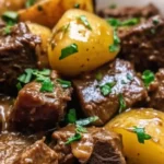 Garlic butter beef bites served with crispy roasted potatoes in a skillet, garnished with fresh herbs.
