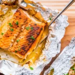 Golden Sheet Pan Lemon Garlic Butter Salmon with flaky fillets nestled among roasted asparagus and cherry tomatoes, glistening with zesty lemon slices and herb-infused garlic butter, ready for an easy healthy dinner on one pan.