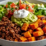 Healthy meal prep steak burrito bowls with seasoned steak, lettuce, rice, beans, and fresh toppings arranged in containers.