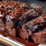 Hot fudge brownie bread loaf sliced on white parchment revealing ultra-fudgy dark crumb, made with one box brownie mix, one jar hot fudge sauce, three eggs, and canola oil baked at 350°F