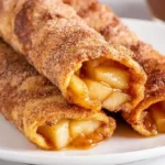 Air fryer apple pie taquitos easy 23-minute dessert 5 ingredients — 1 can 21-ounce apple pie filling 6 medium soft flour tortillas 4 tablespoons melted butter half cup granulated sugar 1 tablespoon ground cinnamon, lay tortillas flat spoon 2 tablespoons apple pie filling center each tortilla, roll tightly brush melted butter all over outside, shallow dish stir together sugar cinnamon roll buttered taquito entire outside coated, place air fryer basket seam side down no overlapping, air fry 350°F 9-11 minutes golden crispy bottom, tongs flip air fry additional 3-4 minutes all sides crispy, cool 5 minutes served warm caramel sauce dipping ice cream vanilla scoop alongside