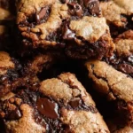 Brown butter brookies with fudgy brownie layer and chewy chocolate chip cookie base stacked golden edges melty chocolate chips flaky sea salt