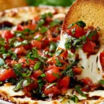 Bruschetta Dip shallow serving dish with a creamy whipped ricotta and Boursin cheese base topped with juicy diced tomatoes, fresh basil, and a glossy balsamic glaze drizzle, served alongside toasted baguette slices