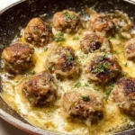 French Onion Meatballs with caramelized onions rich beef gravy melted Gruyere and mozzarella cheese garnished with fresh thyme and baguette