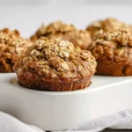 Healthy banana oatmeal muffins with rolled oats topping cooling on a wire rack next to fresh ripe bananas
