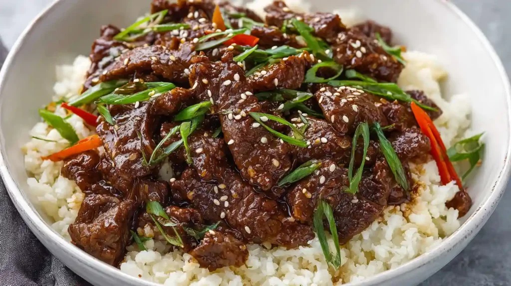 Mongolian Beef with tender flank steak strips glossy brown sauce green onions sesame seeds and red chili flakes served over white rice