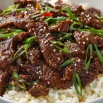 Mongolian Beef with tender flank steak strips glossy brown sauce green onions sesame seeds and red chili flakes served over white rice