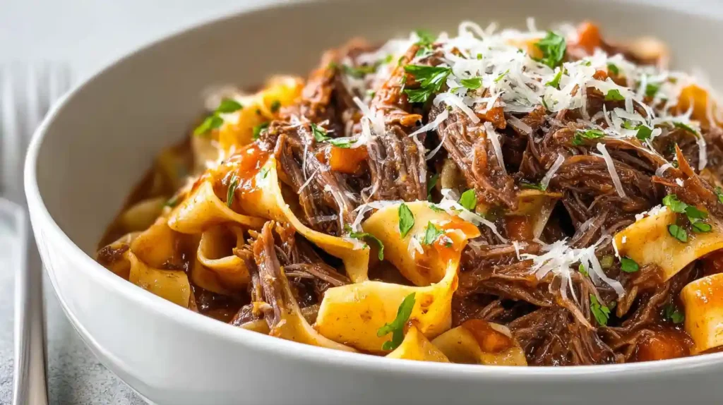 Slow cooker beef ragu with fall-apart shredded chuck roast in rich red wine tomato sauce served over pappardelle pasta