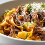 Slow cooker beef ragu with fall-apart shredded chuck roast in rich red wine tomato sauce served over pappardelle pasta