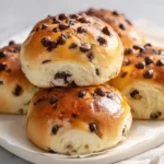 The fluffiest chocolate chip milk buns golden pillowy and soft fresh out of the oven loaded with melted chocolate chips on a parchment lined baking pan